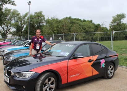 Richard Allen stands beside an offical paralympics car decked out in orange and black.