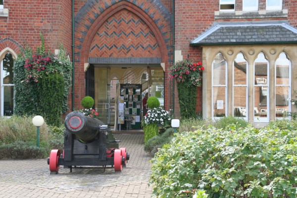 Arched entrance to a building, with a cannon in the foreground.