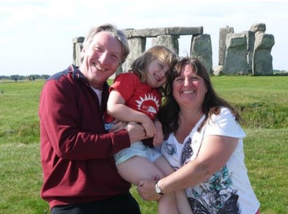 Photo of Rowena and her husband Mark holding Kerensa, in front of Stonehenge all looking very happy.