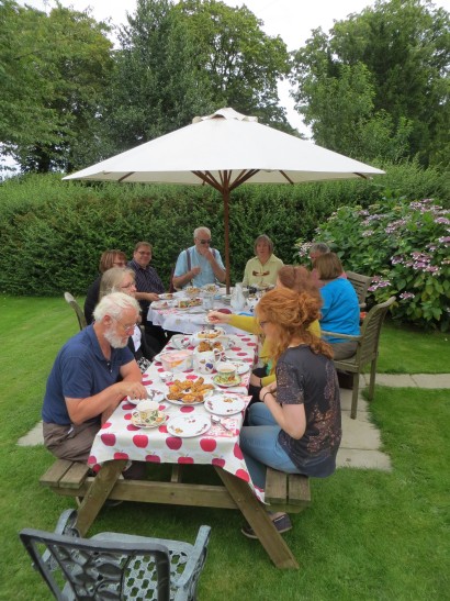 The group enjoying a meal, along a garden bench and table