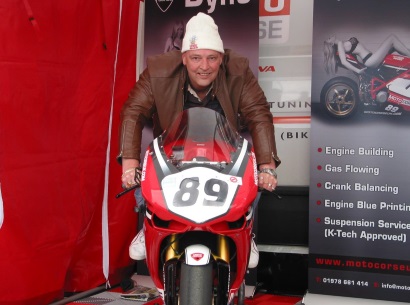 Colin sits on a racing Ducati motorcycle, number 89