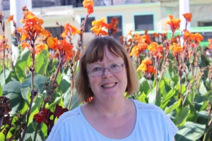 Sally poses in front of some tall, bright orange flowers