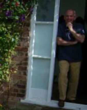 Tony, standing, hand on chin in a doorway