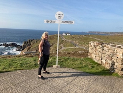 Angie, standing by a Land's end sign showing distances to New York and John O'Groats
