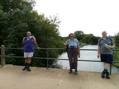 Three stand on a bridge above a river