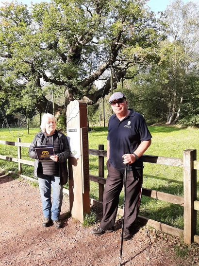 Two member stand by a sign post in from of the major oak.