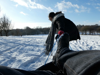 A person pulls a sled over a flat snowy field