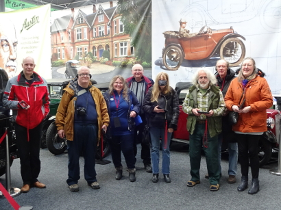 The group stand in front of a pair of classic british cars
