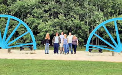 The group stand in a park between two large blue half wheels