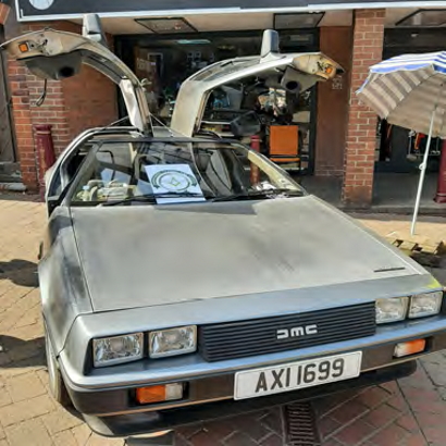 A grey DeLorean car with it gull-wing doors open
