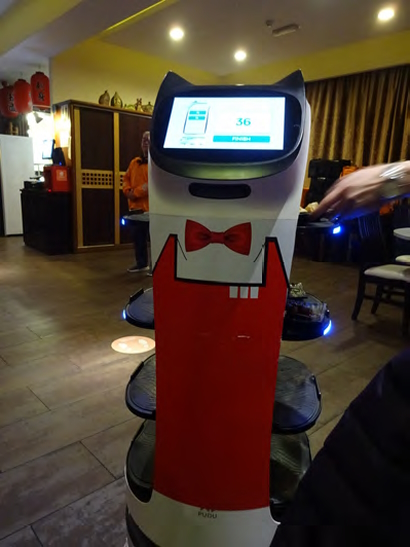 A robot, essentially a moving pedestal with a touchscreen on top, painted in red and white with a red bow tie.