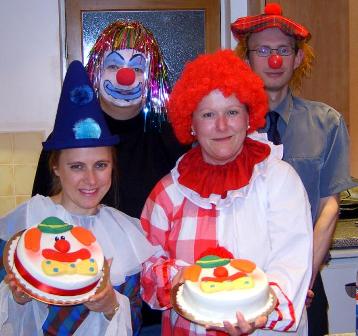 Picture of members dressed at clowns at the Humour Month Party with a couple of cakes, also decorated as clown's faces.