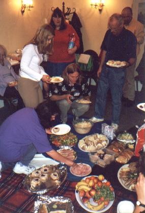 Picture of members helping themselves to a picnic laid out on the floor inside a room of the Forte Hotel.