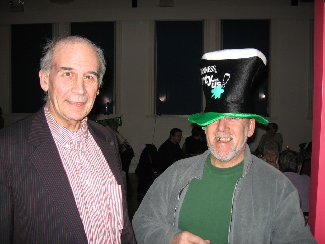 Picture of two members at the dinner. One is wearing a tall hat that looks like a pint of guinness.