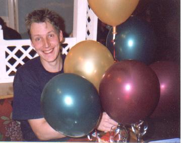 Picture of Neil with half a dozen brightly coloured and shiny balloons