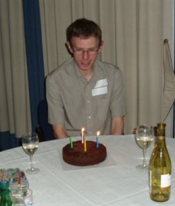 Picture of Paul behind a table with a chocolate cake and a couple of wine glasses