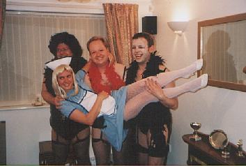 Picture of three the group in high heels and suspenders holding a fourth in nurse's outfit